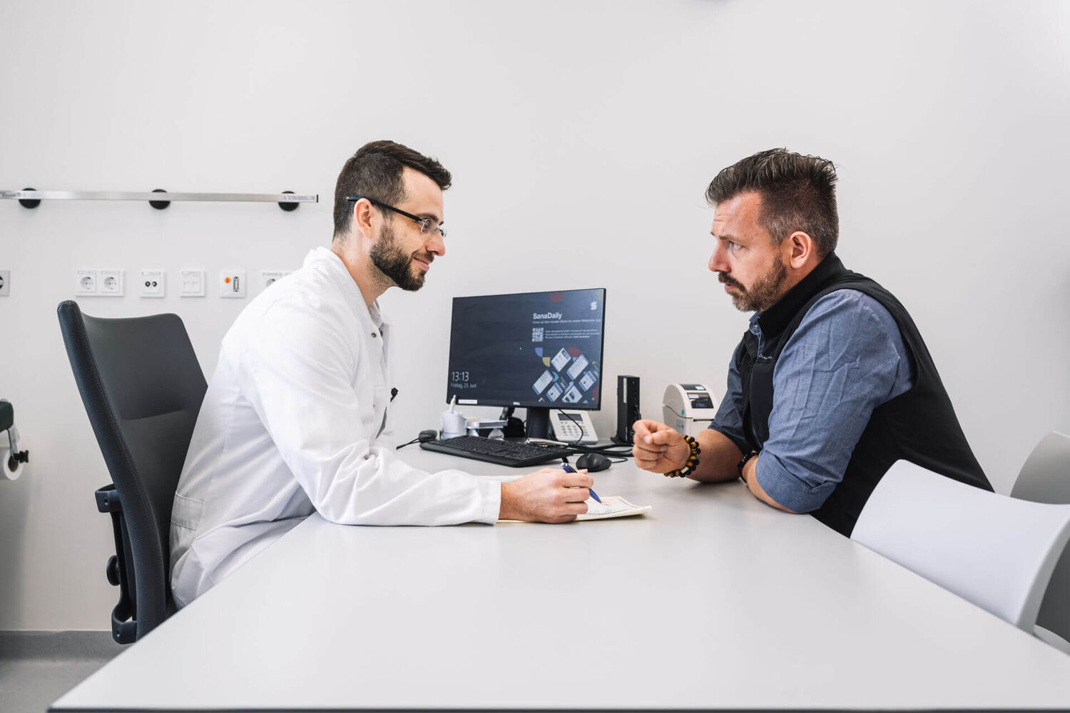 Das Bild zeigt einen Logopäden im Gespräch mit einem Patienten.