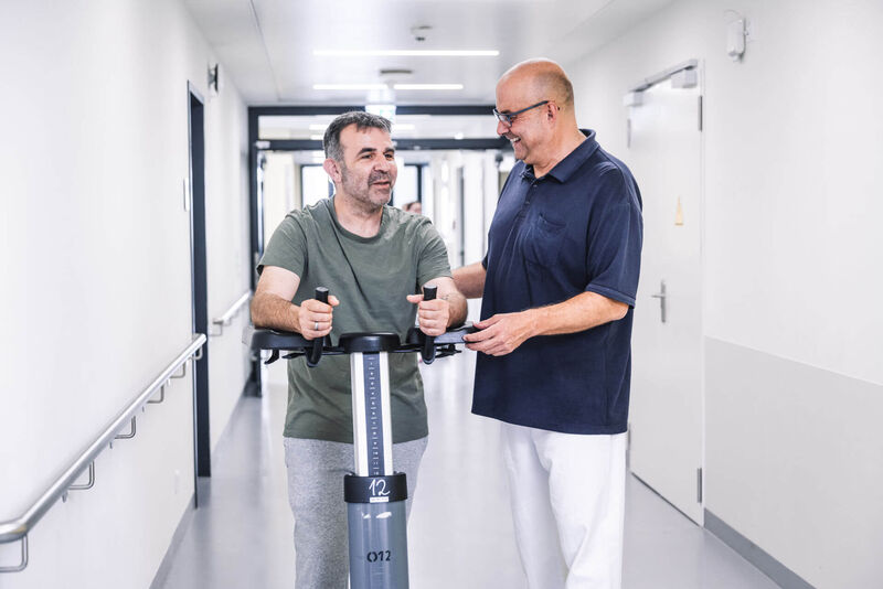 Das Bild zeigt einen Mitarbeiter im Gespräch mit einem Patienten.