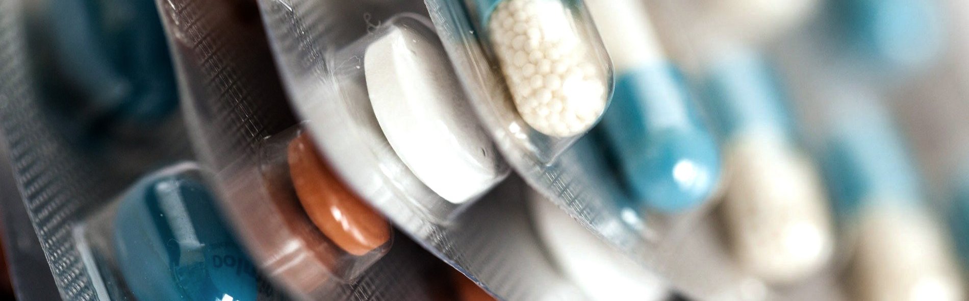 Bild von fünf übereinander gestapelten Tabletten-Verpackungen in den Farben blau, weiß und orange. 