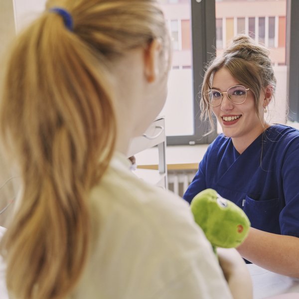 Foto einer Kinderkrankenpflegerin, die sich um eine junge Patientin kümmert.