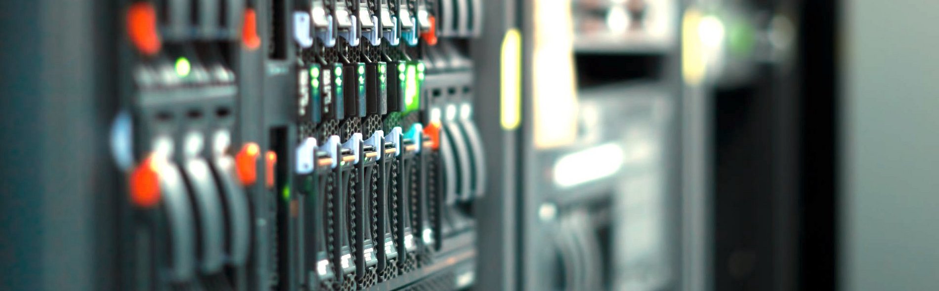 Bild von Steuerraum im Bereich Gebäudetechnik. Der Anschnitt zeigt Knöpfe und Hebel, die teilweise in den Farben blau, grün und orange leuchten.