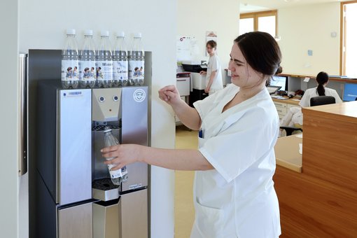 Foto einer Pflegekraft, die einen Wasserspender in den Sana Kliniken Niederlausitz bedient.