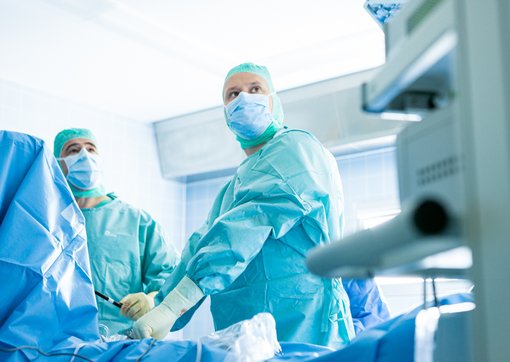 Foto zweier Ärzte in OP-Kleidung und mit Gummihandschuhen im OP-Saal.