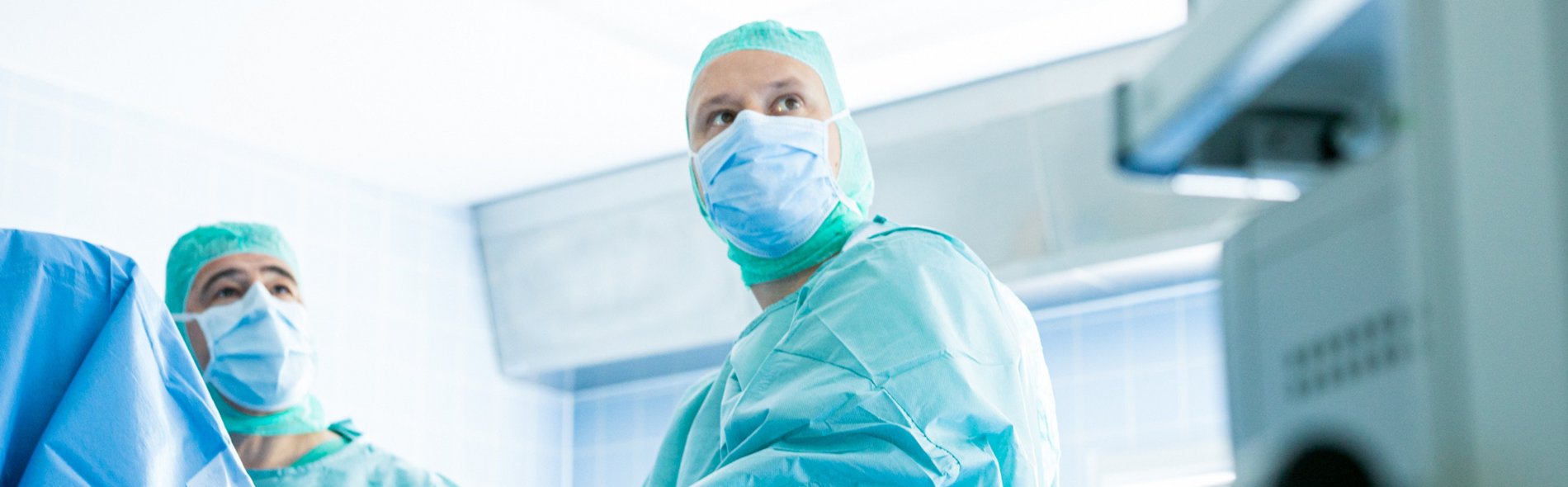 Foto zweier Ärzte in OP-Kleidung und mit Gummihandschuhen im OP-Saal.