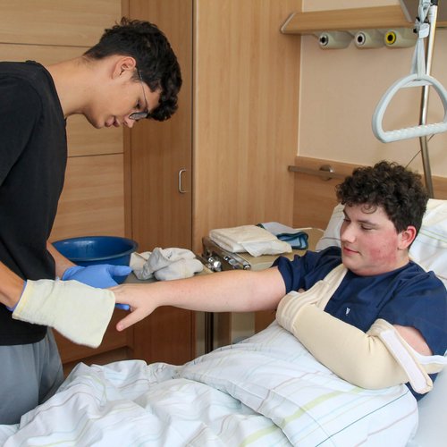 Ein Schüler übt das Waschen an einem Mitschüler.