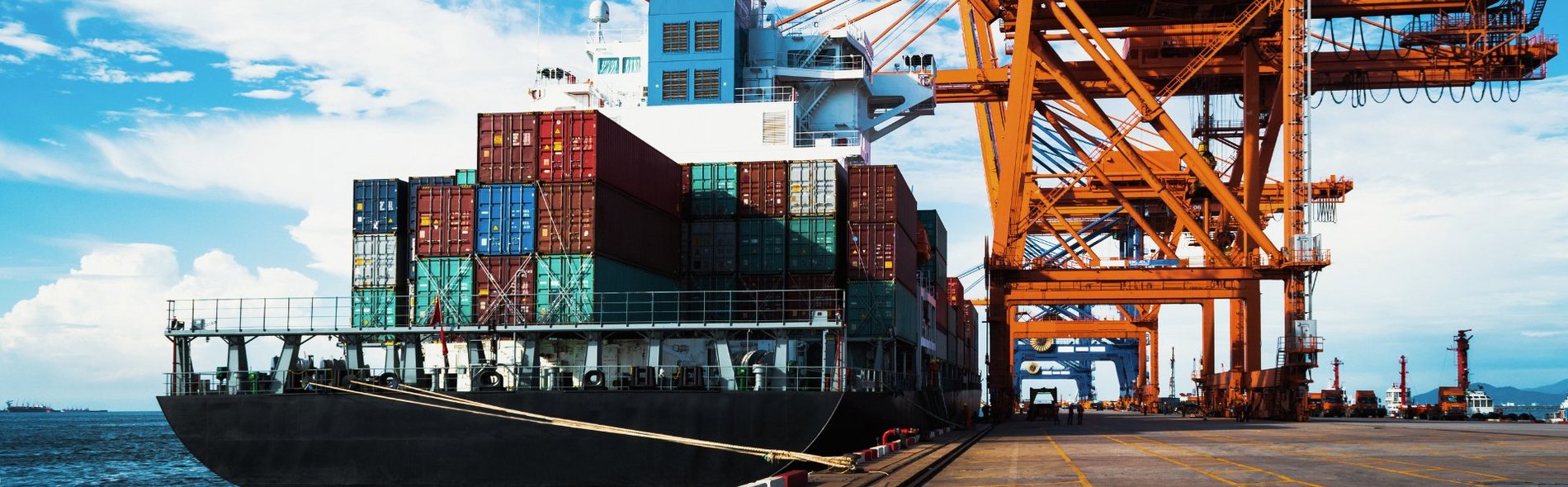 Foto eines großen Frachtschiffs beim Entladen und Beladen einer Containerladung im Hafenterminal.