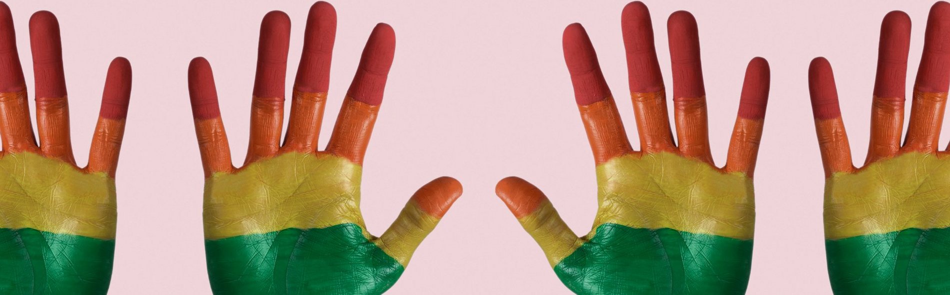 Foto von vier Händen, bemalt mit den bunten Farben der LGBTIQ-Bewegung.