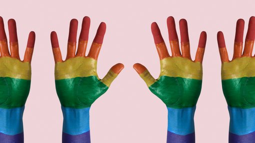 Foto von vier Händen, bemalt mit den bunten Farben der LGBTIQ-Bewegung.